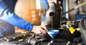 auto mechanic pouring motor oil into engine