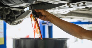 A Pearson Auto employee empties old auto oil into a pan.