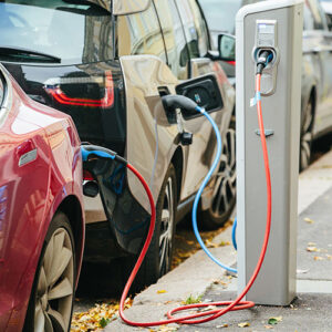 Red and black electric vehicles are plugged in and charging