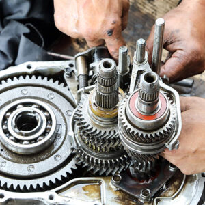 A pair of hands works on a car transmission.